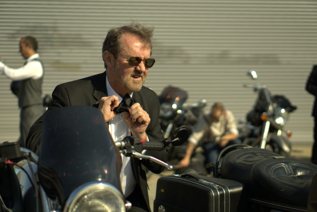 A rider ties his tie using the Mirror on his Motorcycle